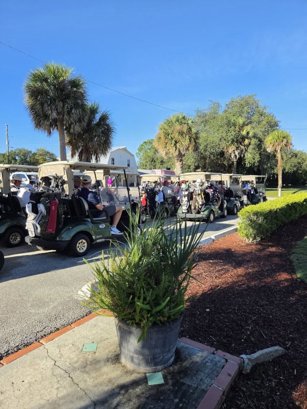 A queue of carts, heavily laden with passengers and golf clubs, eagerly awaits the start of the tournament.