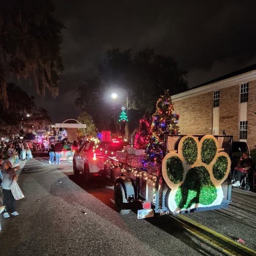 The Animal League trailer passes through Leesburg. It is adorned with decorated trees, presents, stockings, tinsel, lights, and our big, green paw logo made out of tinsel. The parade is in full swing and many people have gathered to watch.